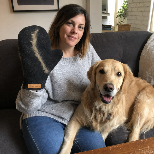 A customer holding the hair remover, coated in golden retriever hair, with her dog beside her on the sofa